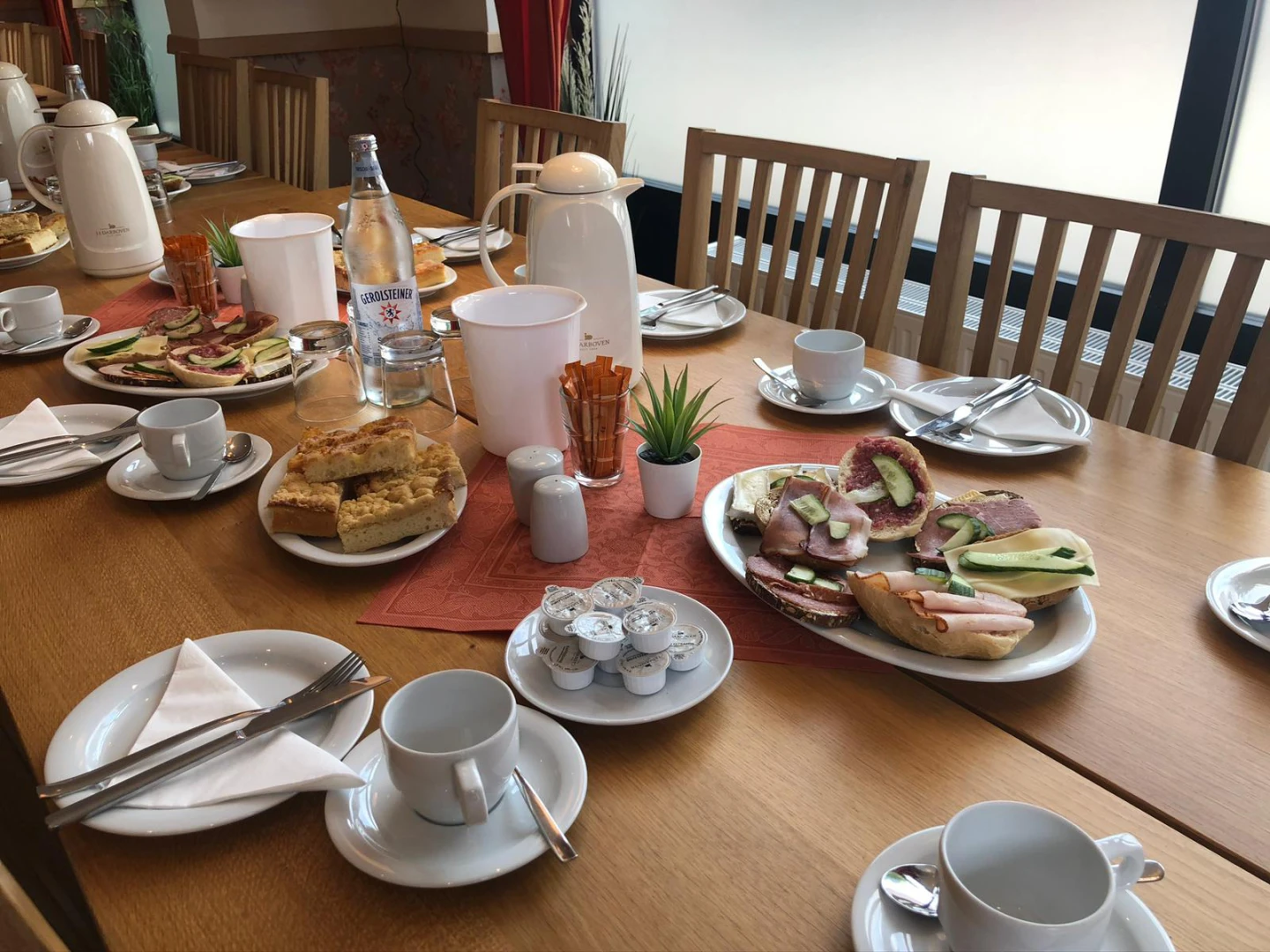 Gedeckter Frühstückstisch mit Brötchen, Kaffee und Kuchen
